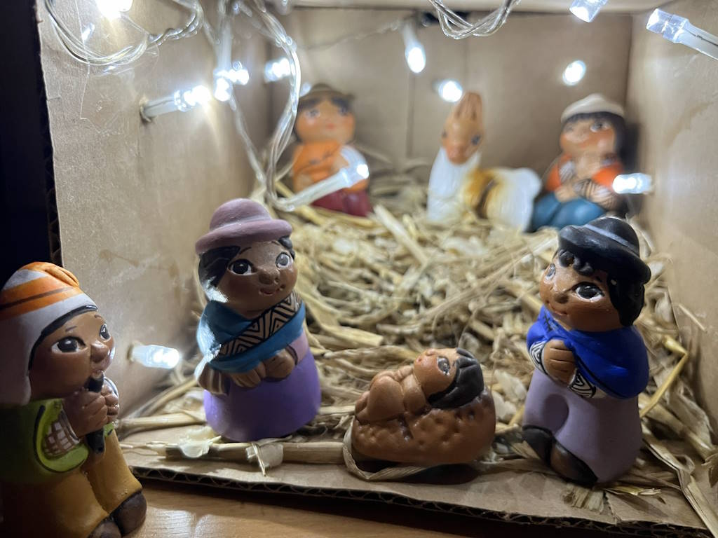 Nativity scene with Andean figures in a cardboard stable with white fairy lights